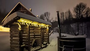A wooden cabin with a snow-covered roof and a chimney, surrounded by snow. - U Kazíků by Interhome (Vysoké nad Jizerou)