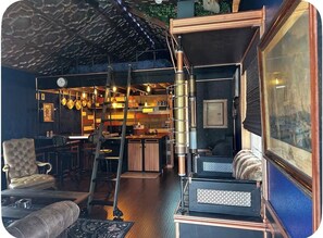 A cozy interior with a bar area, seating, and a kitchen. - Steampunk Tiny House w/ Loft Near Lake Travis (Austin)