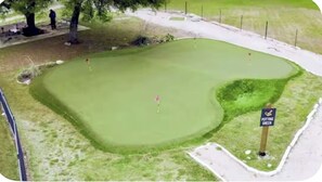 En golfbana med en puttinggreen och en skylt som visar var den ligger.