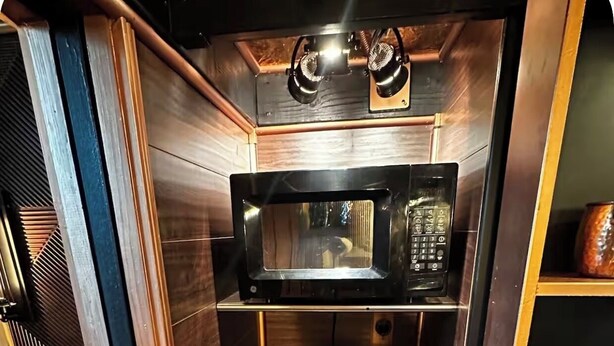 Ett litet, praktiskt kök med mikrovågsugn, kaffebryggare och hyllor för förvaring.