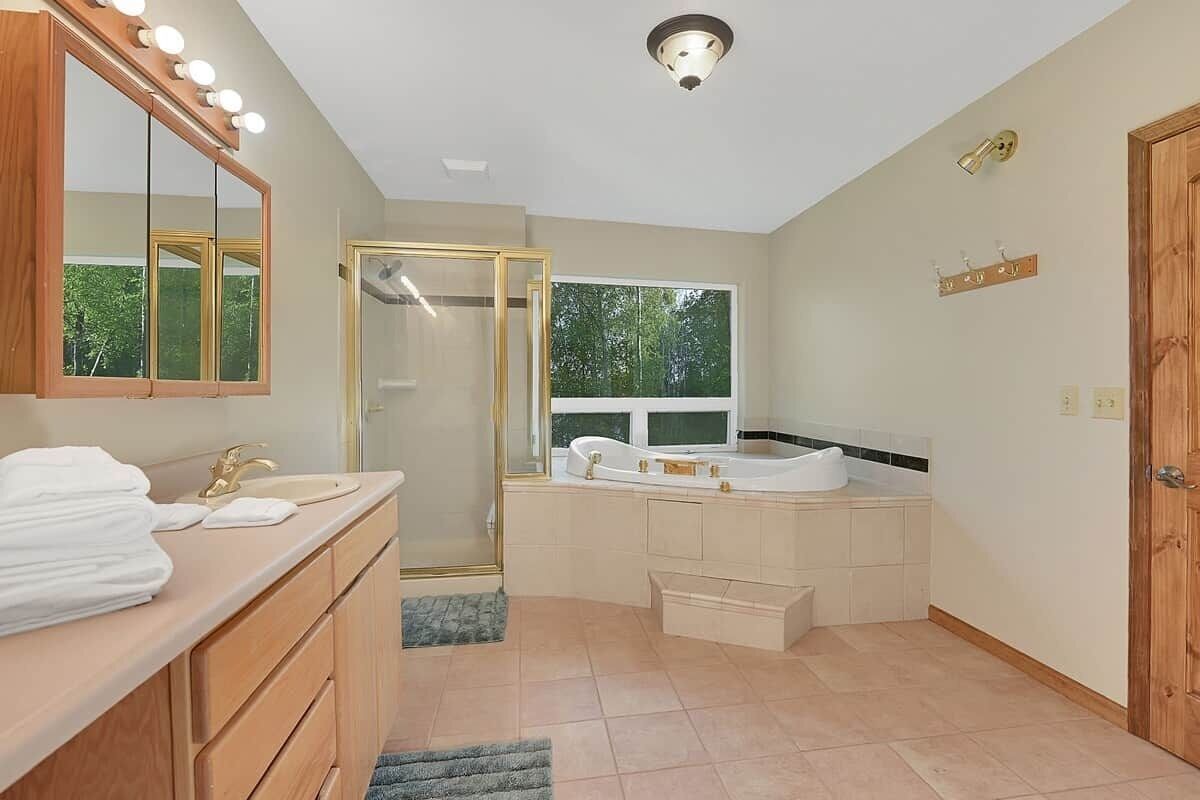 A modern bathroom with a vanity, a large mirror, a shower enclosure, and a bathtub.
