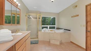 A modern bathroom with a vanity, a large mirror, a shower enclosure, and a bathtub.