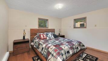 Une chambre à coucher avec un lit en bois, deux tables de chevet, une fenêtre et un luminaire au plafond.