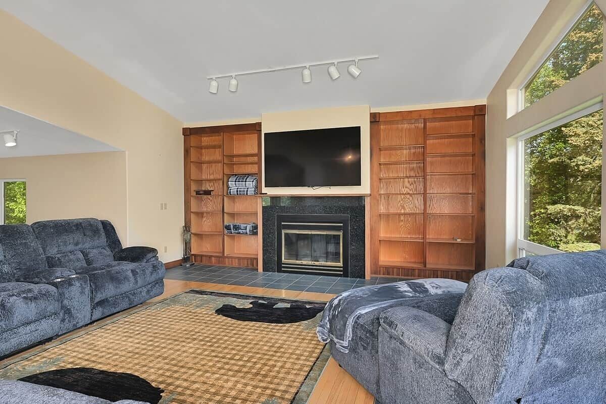 A living room with a fireplace, a flat-screen TV, and two sofas.