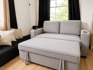 A modern living room with a grey sofa, a black couch, and a window with curtains. - Modern home fast Starlink wi-Fi, Modern Home, free breakfast, near the beach (San Jose)