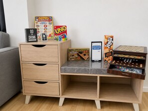 A wooden desk with drawers, a smartphone, and various board games. - Modern home fast Starlink wi-Fi, Modern Home, free breakfast, near the beach (San Jose)
