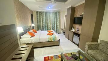 Una habitación de hotel con cama, sofá, televisor, escritorio y ventilador de techo.