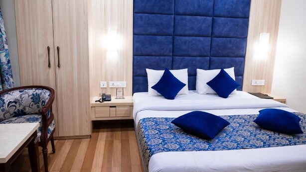 Une chambre d’hôtel comprenant un lit, des tables de chevet, une chaise et une armoire.