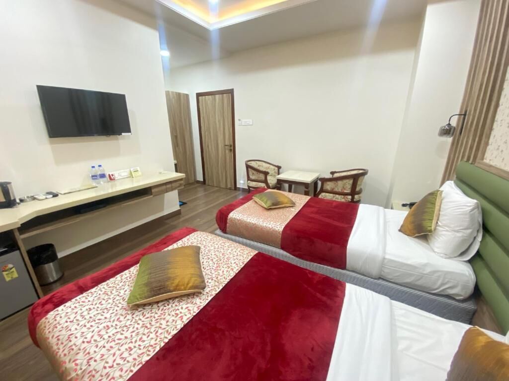 Habitación de hotel con dos camas, un escritorio, una silla, un televisor y una puerta.