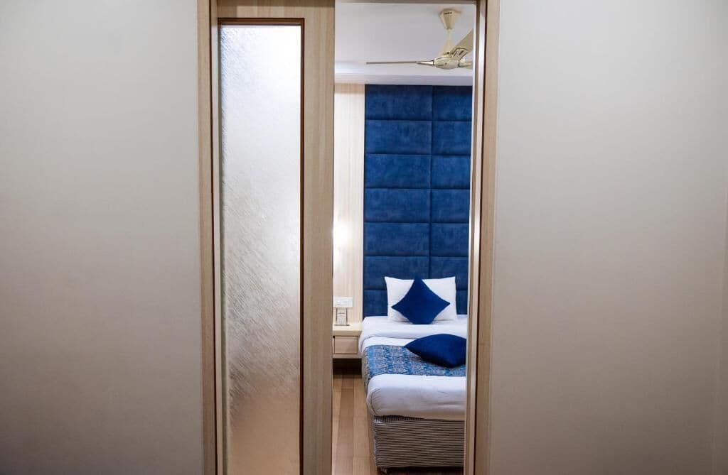 A narrow hallway leading to a bedroom with a tufted headboard and a bed with blue bedding.