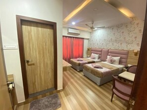 Un dormitorio con una puerta de madera, dos camas con cabeceros rosa, un ventilador de techo y un papel tapiz estampado.