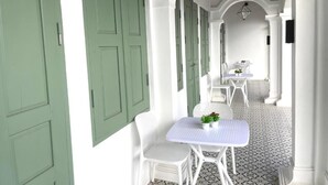 A corridor with white walls, green doors, and white furniture. - La Petite Maison Luang Prabang (Luang Prabang)