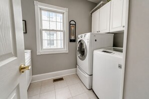 A laundry room with a washing machine, dryer, and a window.