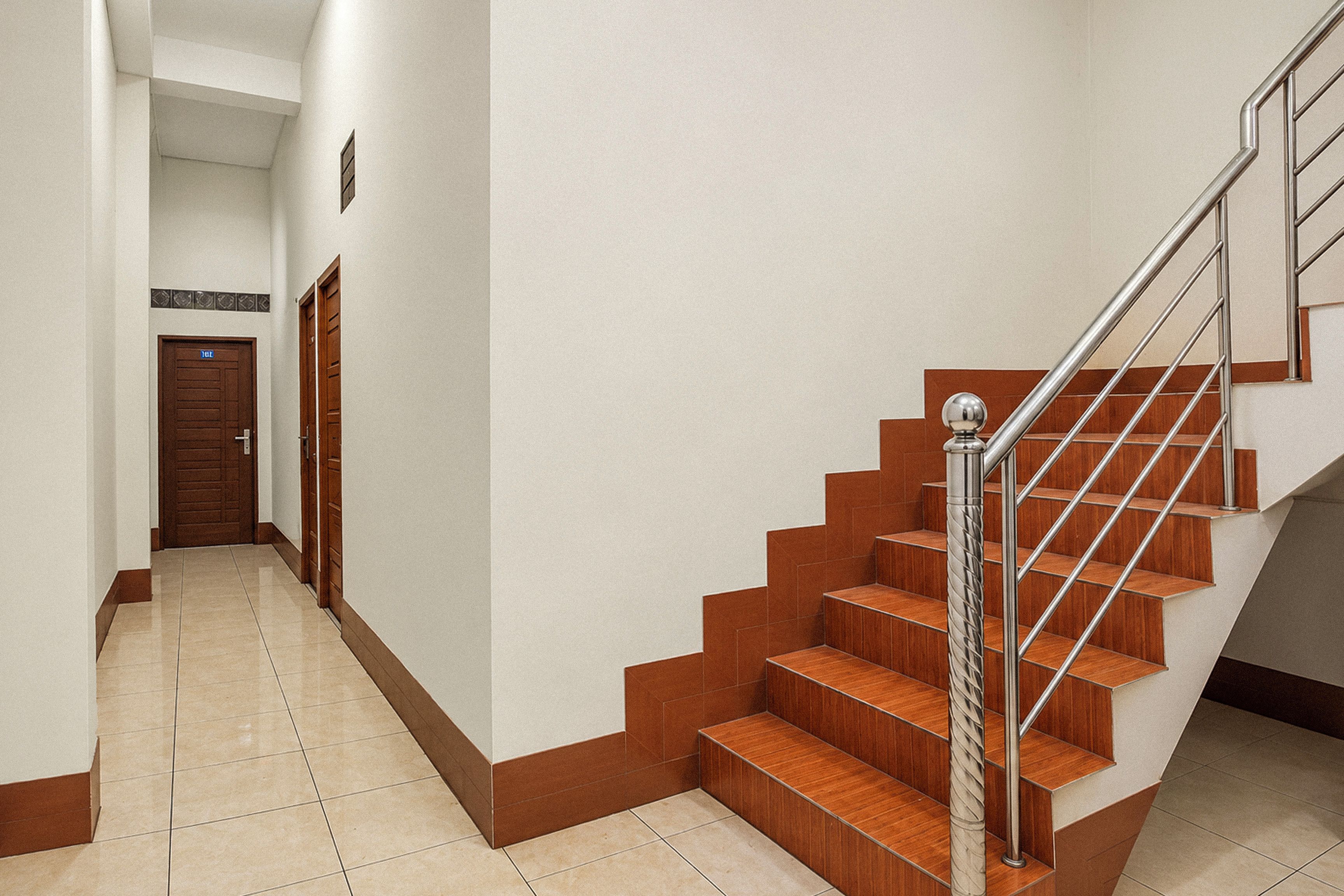 A hallway leading to a staircase with wooden steps and metal railings.