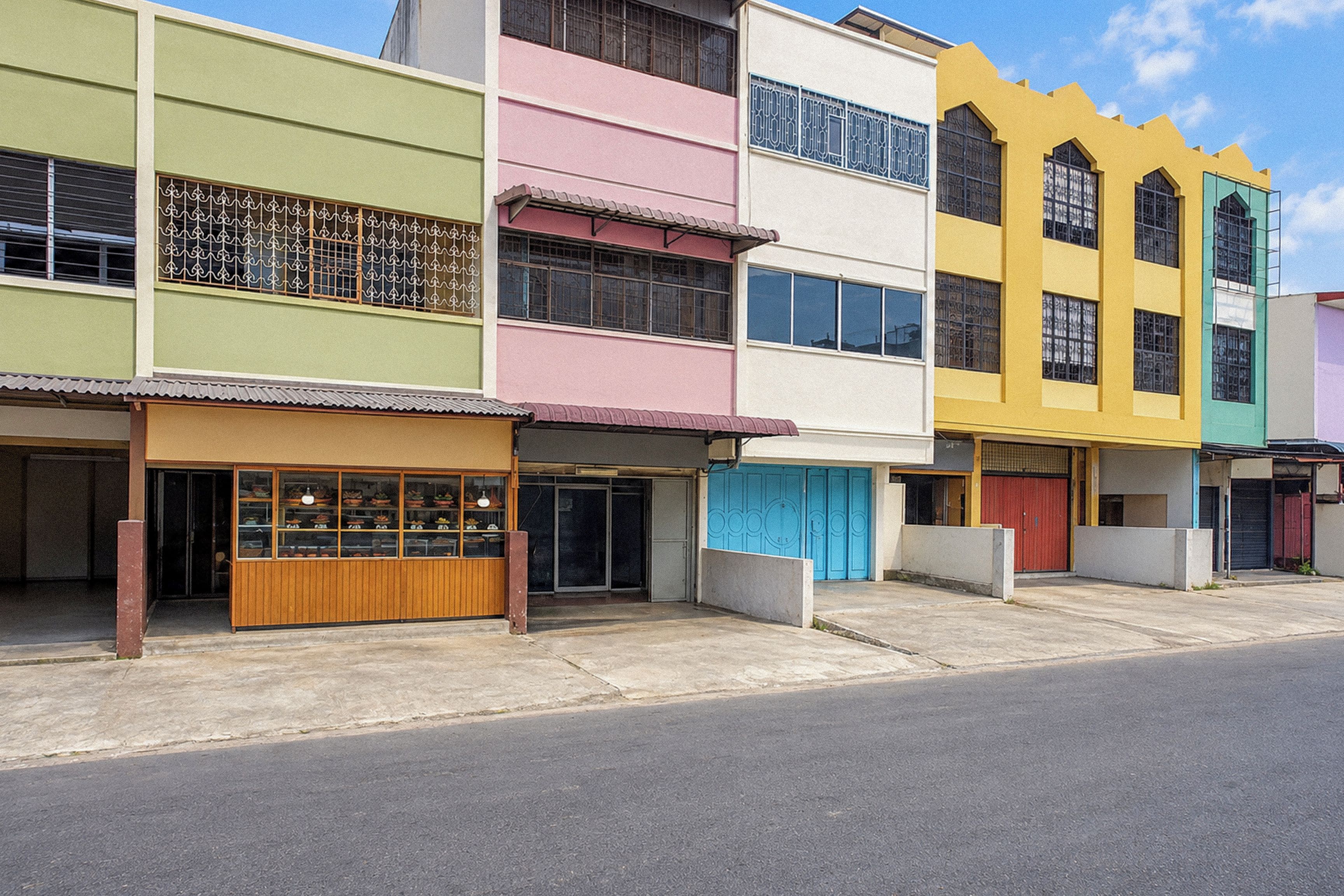 A row of colorful buildings with storefronts, each with a distinct color.