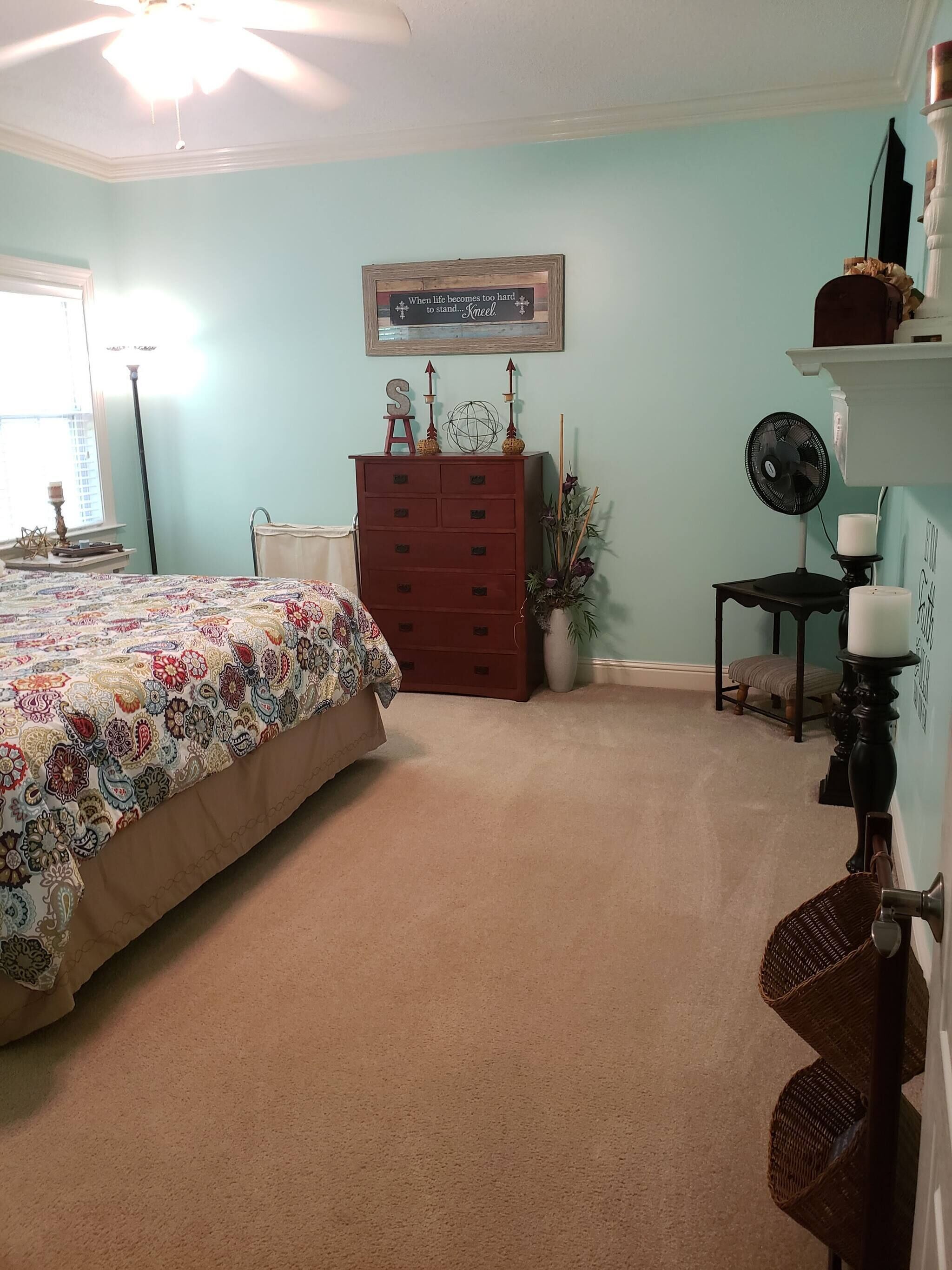 A bedroom with a bed, dresser, and a ceiling fan.