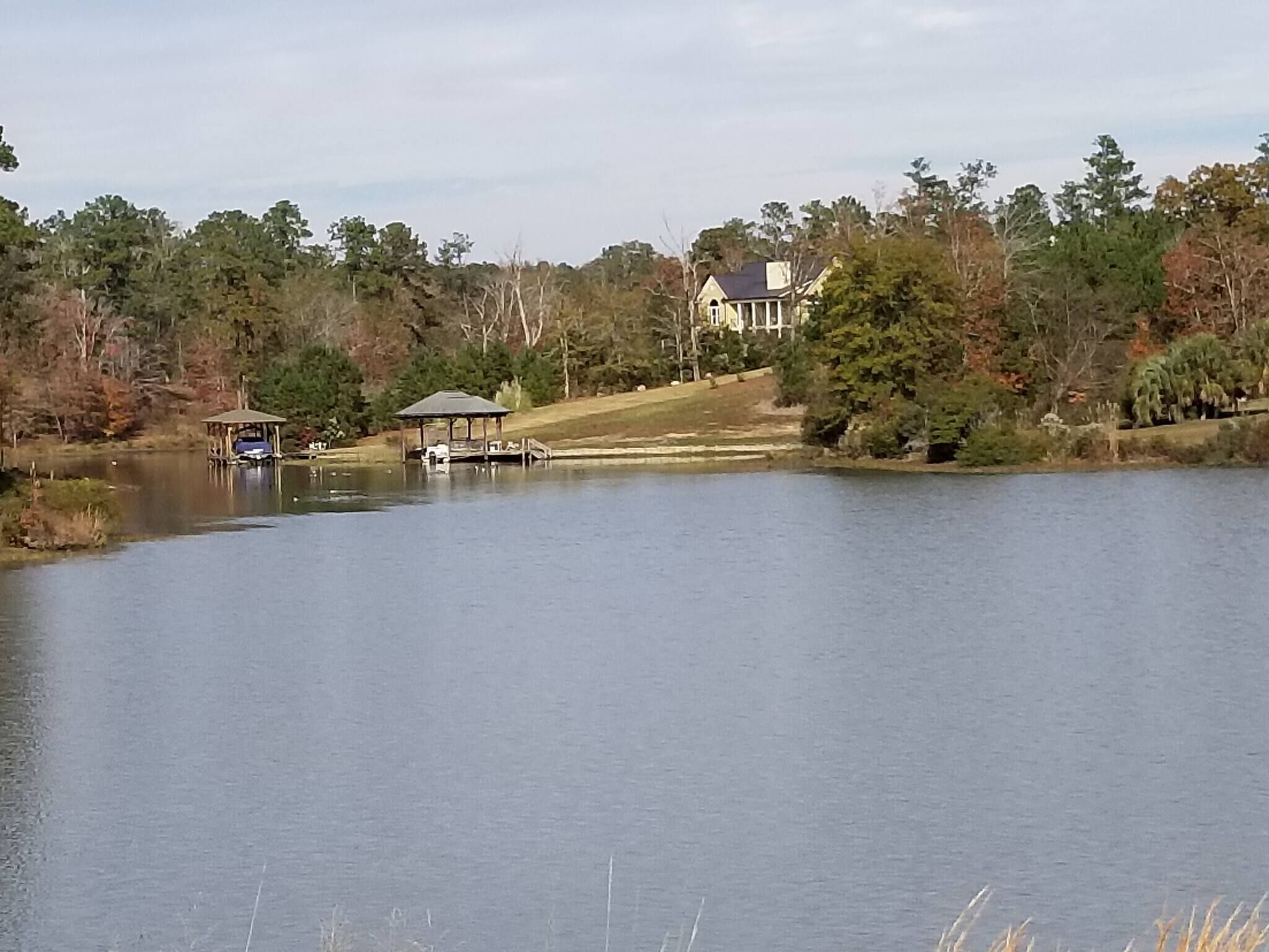 A calm lake with a gazebo and a house in the background.