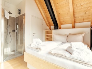 A bedroom with a bed, a shower, and a wooden ceiling. - Chalet Nr. 3 mit 3 SZ, Sauna & Whirlpool by Interhome (Niederwölz)