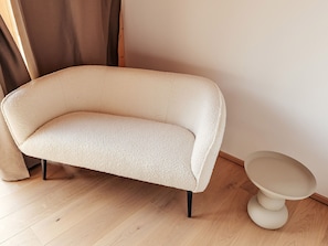 A sofa with a textured fabric and black legs, positioned next to a round table with a white base. - Chalet Nr. 3 mit 3 SZ, Sauna & Whirlpool by Interhome (Niederwölz)
