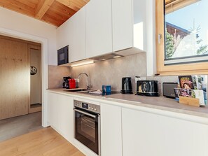 A modern kitchen with white cabinetry, a built-in oven, a microwave, and a coffee maker. - Chalet Nr. 6 für 2 Personen mit Sauna by Interhome (Niederwölz)