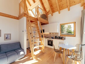 Ein kompakter Wohnbereich mit Schlafgalerie, einer Küchenzeile, einer Essecke und einem Sofa.