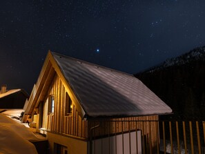 Eine Holzhütte mit geneigtem Dach, einem Fenster und einer Tür.