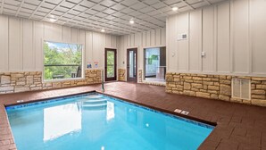 A swimming pool with a stone wall and a view of greenery outside. - Luxury Cabin w/Pool, Hot Tub, Game Room, Bar, Movie Room & Mountain Views (Sevierville)