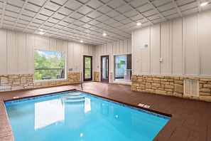 Ein Swimmingpool mit einer Steinmauer und Blick auf Grünflächen.