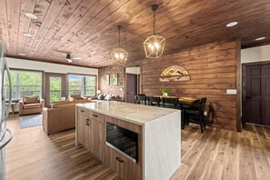 A spacious kitchen with wooden flooring, a central island, and pendant lighting. - The Ridgeline Reserve • Luxe Lodge w/ Private Indoor Pool • Top 5% (Sevierville)