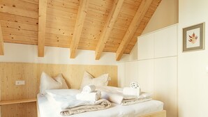 Une chambre à coucher avec un cadre en bois, un lit, des oreillers et des serviettes soigneusement pliées.