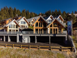 A row of wooden cabins with large windows, a covered walkway, and a view of the forest. - Chalet Nr. 7 mit 3 Schlafzimmern und Sauna by Interhome (Niederwölz)