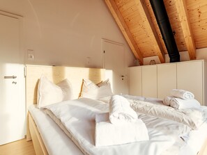 A bedroom with a wooden ceiling, a bed with white bedding, and a wardrobe. - Chalet Nr. 7 mit 3 Schlafzimmern und Sauna by Interhome (Niederwölz)
