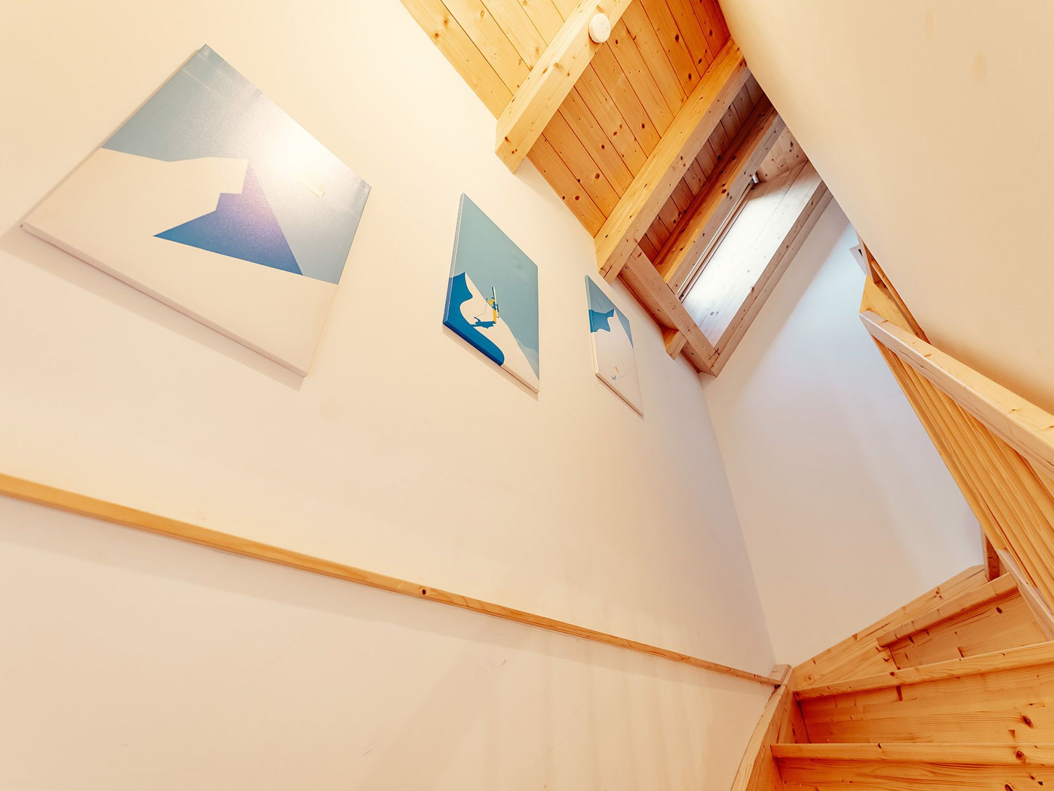 A staircase leading to a loft with wooden beams and a skylight.