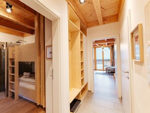 Ein Holzinnenraum mit einem Stockbett, eingebauten Regalen und einem sichtbaren Badezimmer.