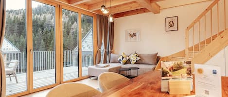 A wooden interior with a sofa, a dining table, and a staircase.
