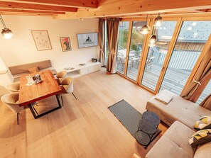 Ein modernes Interieur mit einem Holztisch, einer Couch und einem großen Fenster mit Vorhängen.