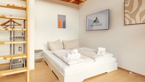 Ein Schlafzimmer mit einem Bett, einer Holzhockerregal, einem gerahmten Bild und einer Wanddekoration.