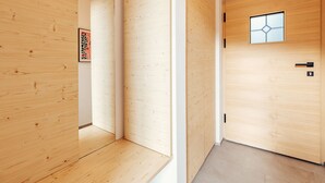 Ein Korridor mit Holzwänden und einer Tür mit geometrischem Fensterdesign.