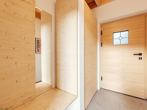 Ein Korridor mit Holzwänden und einer Tür mit geometrischem Fensterdesign.