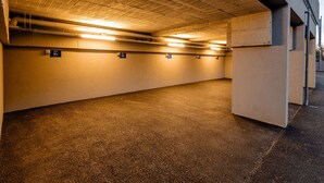 Eine Tiefgarage mit Betonwänden und -decke, beleuchtet durch Deckenleuchten.