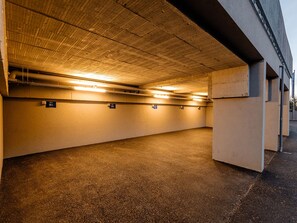 Eine Tiefgarage mit Betonwänden und -decke, beleuchtet durch Deckenleuchten.