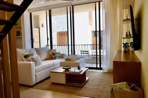 Ein modernes Wohnzimmer mit einer Couch, einem Couchtisch und Blick durch große Schiebetüren auf einen Außenbereich.