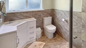 A bathroom with a toilet, sink, and window.