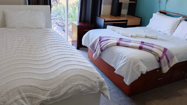 A hotel room with two beds, a desk, and a view of the outdoors.