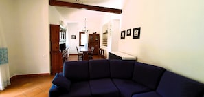 Ein Wohnzimmer mit einem dunkelblauen Sofa, eine Essecke mit einem Holztisch und Stühlen sowie eine Küche mit Schränken und einer Kandelaber.