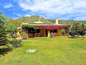 A house with a garden, a patio with chairs, and a mountain in the background. - Villa Carlebia - Private pool and garden. Beaches within walking distance, ideal for families (Sinnai)