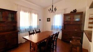 A dining area with a wooden table and chairs, a chandelier, and wooden cabinets. - Villa Carlebia - Private pool and garden. Beaches within walking distance, ideal for families (Sinnai)