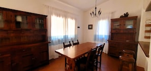 Ein Essbereich mit einem Holztisch, Stühlen, einer Chandelier und Holzschränken.