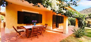 Ein Essbereich im Freien mit Tisch und Stühlen, einer Blumenvase und einer Pergola mit Kletterpflanzen.