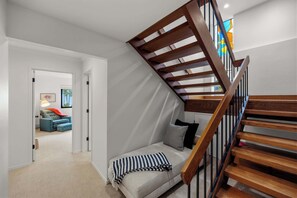 A modern interior with a staircase, a sofa, and a view of a room with a blue sofa and a lamp. - Tide n Timber 4BR 2.5 BA (Pebble Beach)